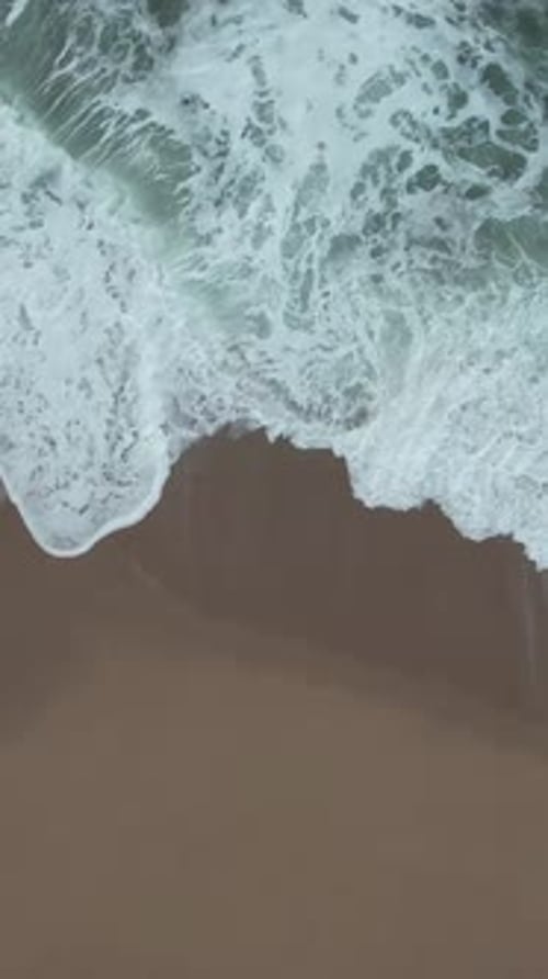Vertical video of Sea Waves Sliding on the Beach Top view