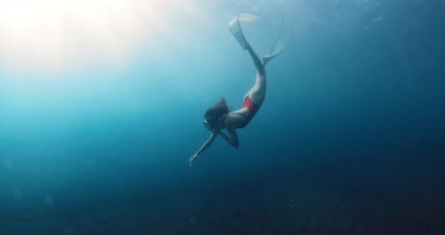 Beauty Woman Freediver in Red Bikini with Diving Fins Swims Underwater in Blue Ocean