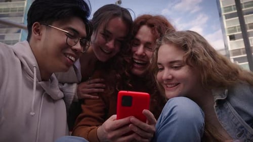 Portrait of Four Smiling Friends Looking at Cell Phone From Below Young People Back to School