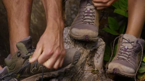 Couple enjoying a hiking adventure tying boots closeup in mountain nature