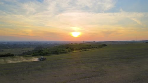 Tractor Spraying Fertilizers with Insecticide Herbicide Chemicals on Agricultural Field at Sunset