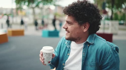 Close-up of man sitting and drinking coffee on busy street modern city background