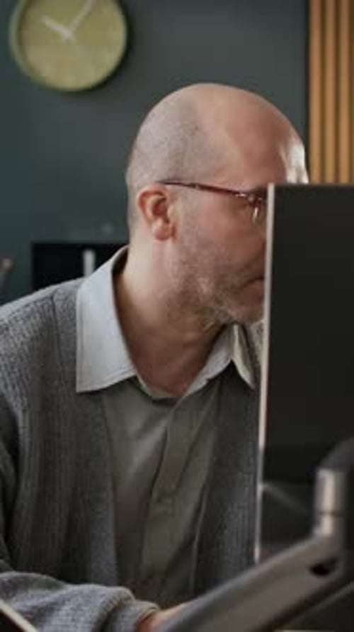 Vertikale eines fokussierten männlichen Programmierers mittleren Alters, der Software im Büro entwickelt