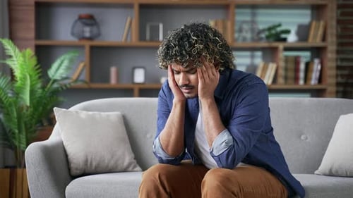 Stressed Man Sitting on Sofa at Home