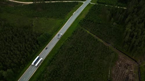 Aerial View of Highway with Trucks Moving Through Forested Landscape Showcasing Transportation and