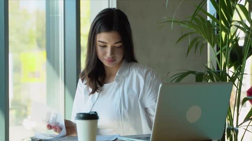 Woman Working at Laptop with Papers and Coffee