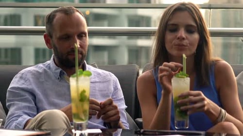 Young Couple Relaxing, Talking and Drinking Cocktails in Bar on Terrace Adult