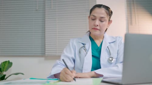 Foreign female doctor uses a laptop computer sitting at a table in the hospital health care and medi