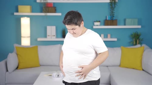 Young Person Rubbing Stomach in Modern Living Room