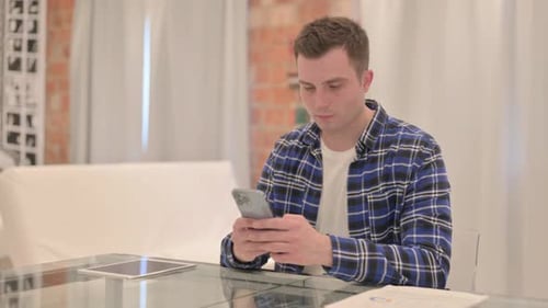 Young Casual Man Using Smartphone at Work