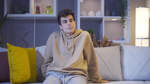 Depressed and lonely man sitting on sofa at home.