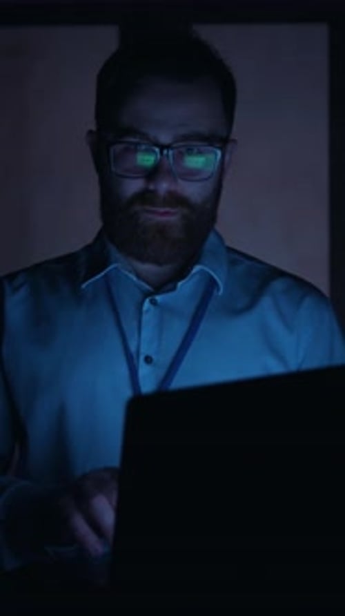 A Professional Man Engaged in Working on His Laptop Within a Modern Office Environment