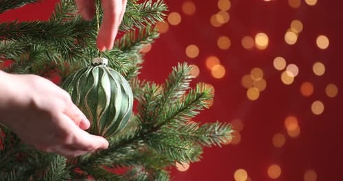 Hand Hanging Green Ornament on Christmas Tree Branch