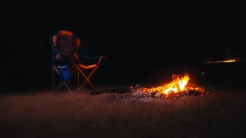Campfire Burning at Night with Camping Chair
