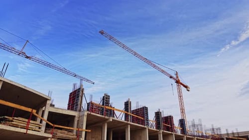 Vista aérea del sitio de construcción con grúas bajo un cielo azul claro