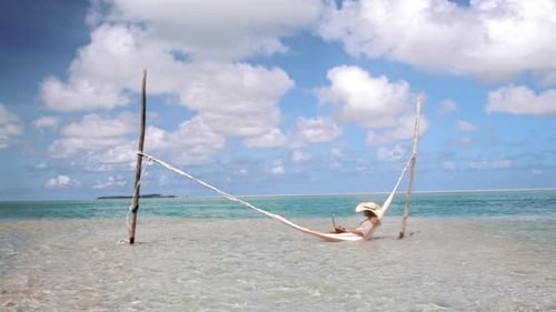 Of Woman Working on Laptop Computer on Hammock in Blue Ocean