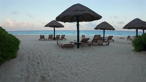 Empty lounge chairs on beach at dusk