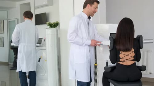 Woman Uses Medical Exercise Device With Doctor