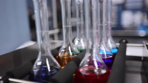 Laboratory flasks mixing colorful liquids on shaker