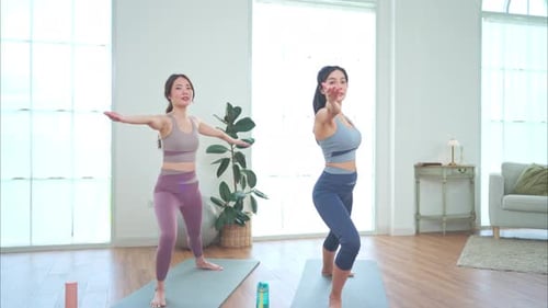 Two Women Practice Yoga in Bright Room