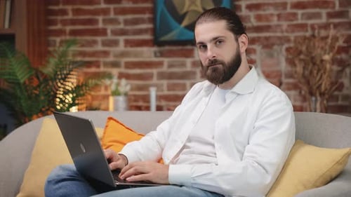 Man with Beard Types on Laptop at Home