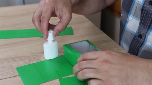 23Hands folding and gluing cardboard cutouts, assembling parts of paper model for creative DIY craft