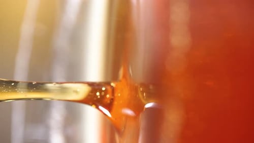 Pingando mel do gotejador de madeira na jarra de vidro Derramando mel. Comida orgânica saudável. Fechamento macro