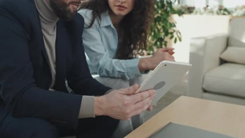 Man and Woman Discussing Tablet in Modern Office