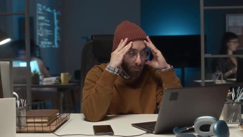 Stressed Man Working Late on Laptop in Office