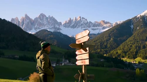 Man Tourist Looking at Wooden Pointer at the Trail in Dolomites Alps Near Santa Maddalena Village