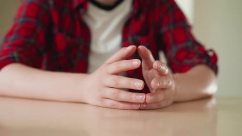 Woman Taps Fingertips Together at Table Closeup