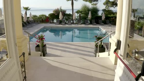 Empty Outdoor Swimming Pool Of A Hotel With Parasols And Lounge Chairs On A Sunny Day. - dolly shot