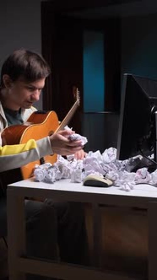Troubled Musician Playing Guitar with Crumpled Paper