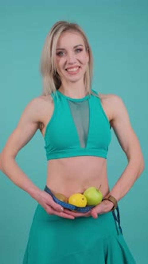Smiling Woman Holds Fruit and Measuring Tape