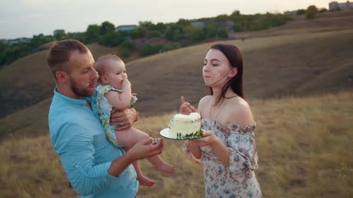 Happy Family with Baby Celebrate First Year Eat Cake in Field at Sunset Autumn and Lifestyle