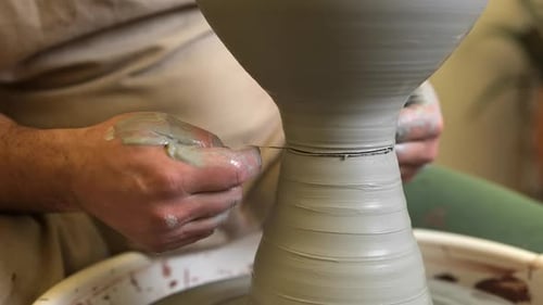 Potter carefully removing completed bowl with tread on workshop pottery wheel
