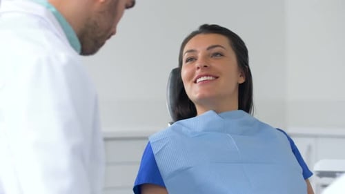 Hispanic dentist explaining treatment to young female patient in clinic office
