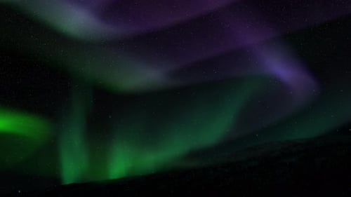 Polarlicht bei Nacht vor einem dunklen, schlichten Vordergrund