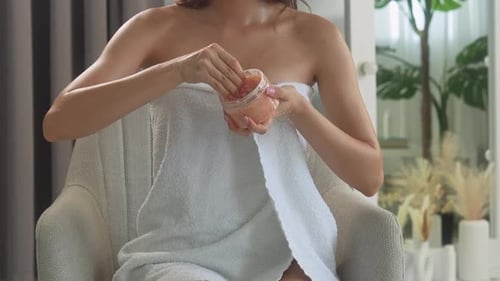 Woman Applies Exfoliating Scrub in Indoor Bathroom Setting