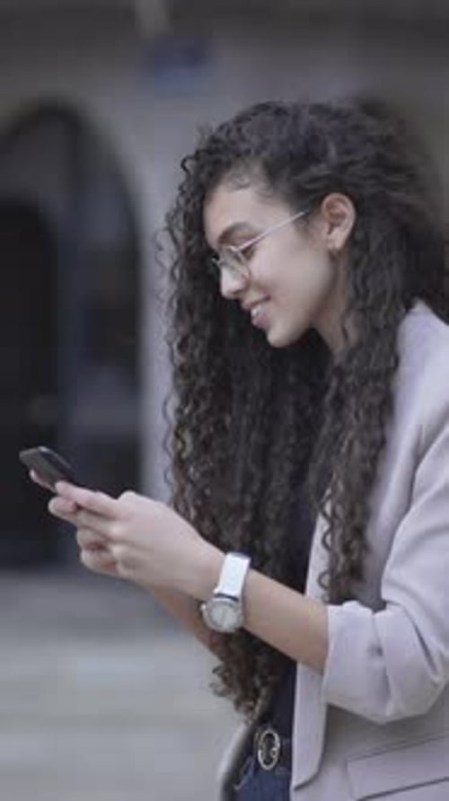 Cheerful Moroccan Girl Is Smiling While Texting On Her Smartphone Outdoor Side View
