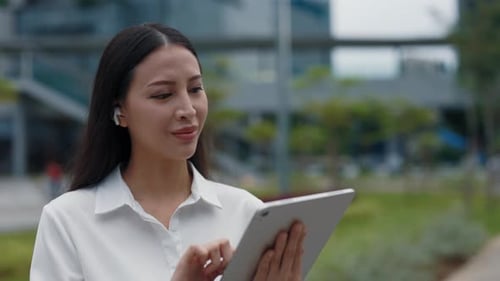 Asian Business Lady Wearing Formal Clothes Standing in the Street and Browsing in Tablet