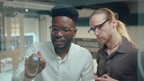 Two Businessmen Discussing Financial Diagram on Glass Office Wall