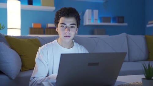 Teen Using Laptop Computer in Living Room at Night
