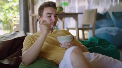 Man Eating from Bowl While Lounging Indoors
