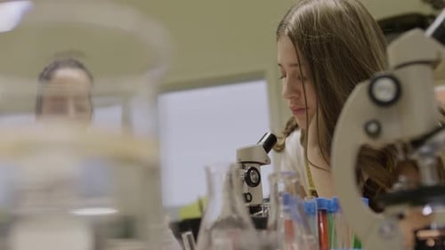 Teenage Girl Studying Science with Microscope in Lab
