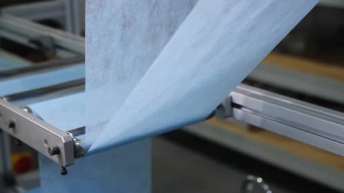 Machine Connects Strips of Blue Material for Facial Masks