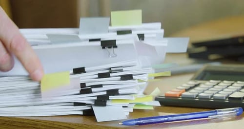 Closeup View of a Hand Fingering a Large Stack of Paper Documents
