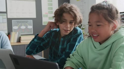 Asian Girl Communicating with her Classmate While Working on Laptop in School