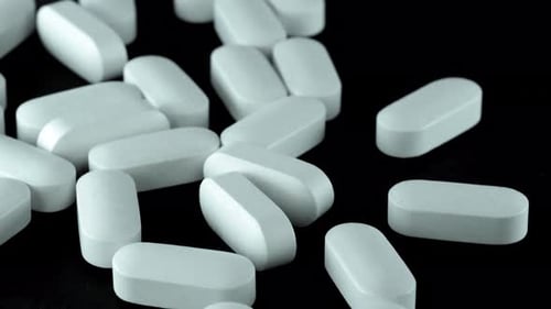 Closeup pan shot of many medication pills on isolated black background. Medical care.