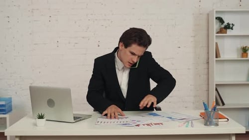 Medium Video of a Young Man Sitting at the Table Having a Business Conversation Phone Call Talking